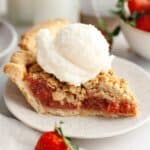 A slice of strawberry rhubarb pie with a scoop of vanilla ice cream.