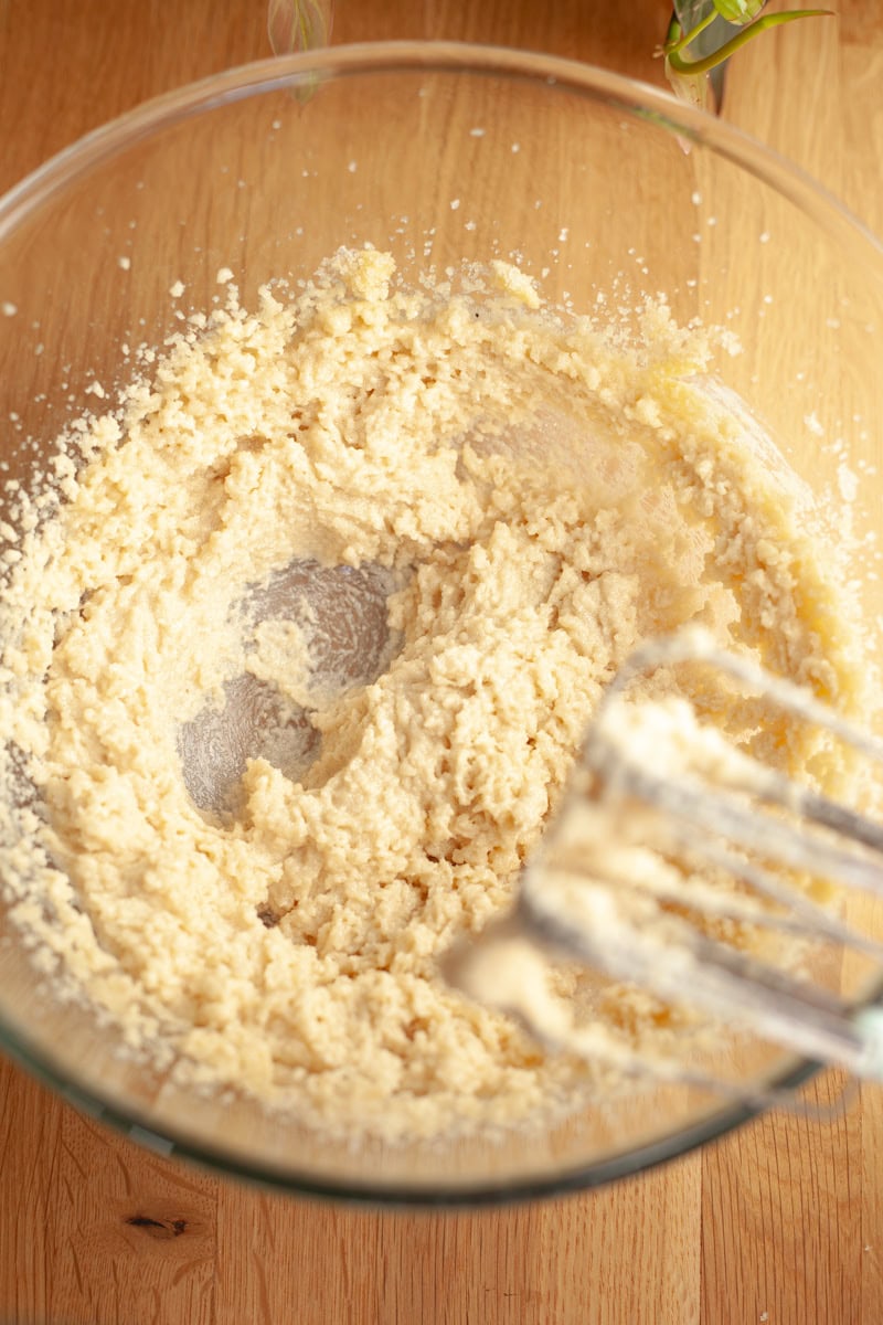 A glass mixing bowl with whipped sugar and butter in it.