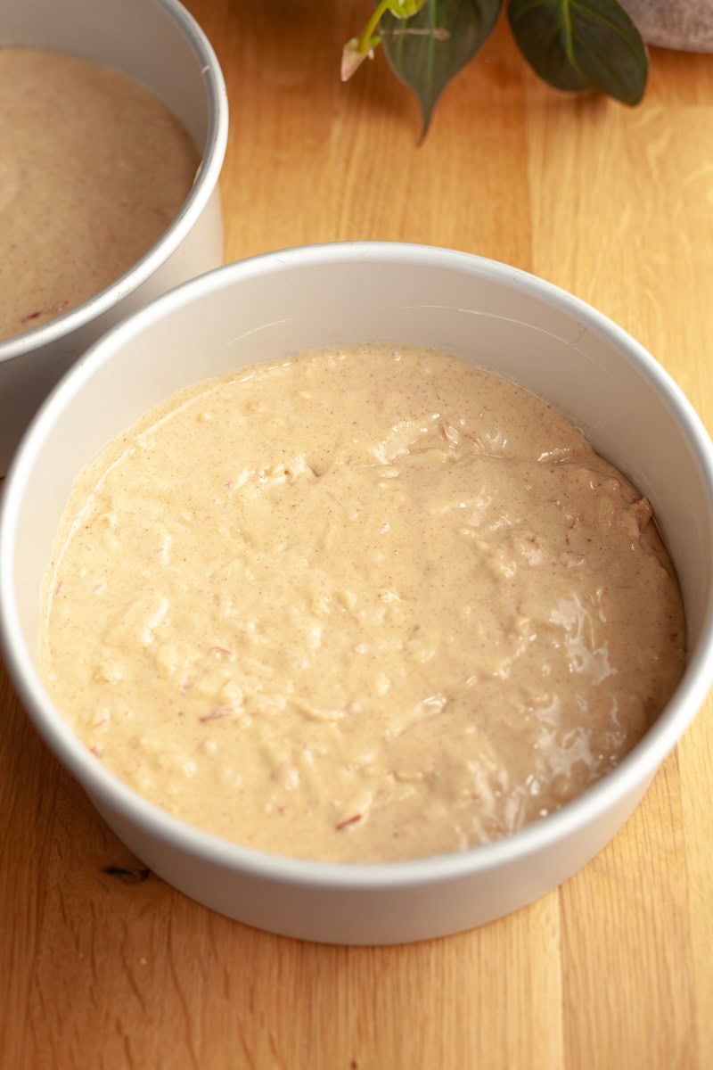 Two round cake pans with unbaked apple cake batter.