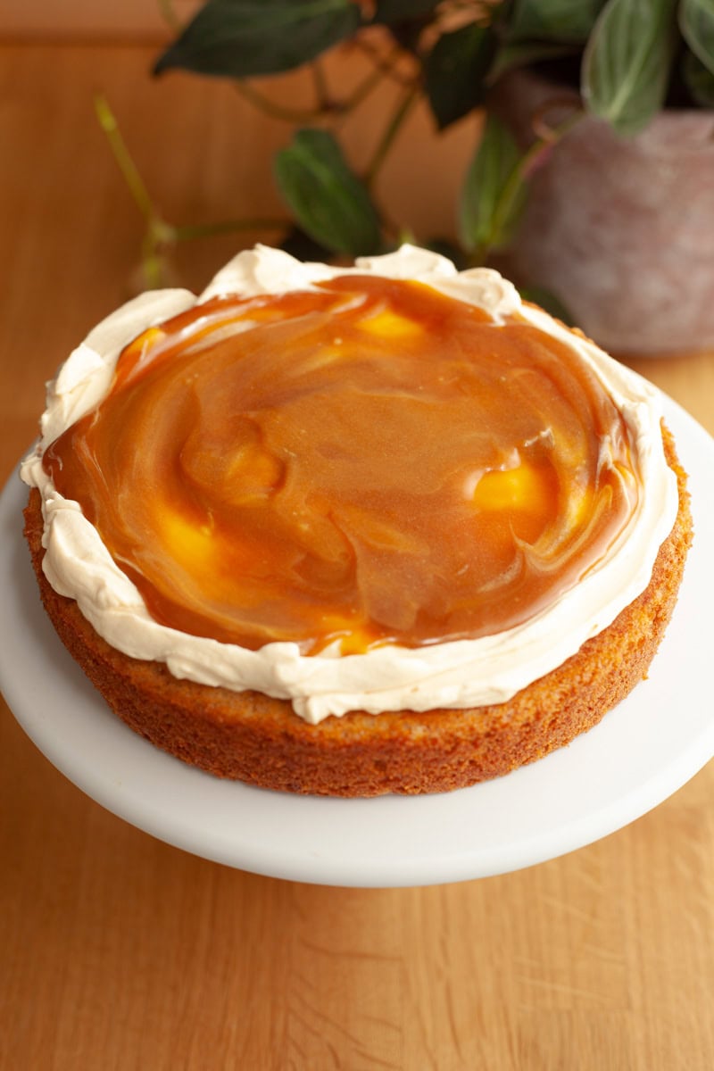 One round cake covered with cream cheese frosting and topped with caramel sauce.