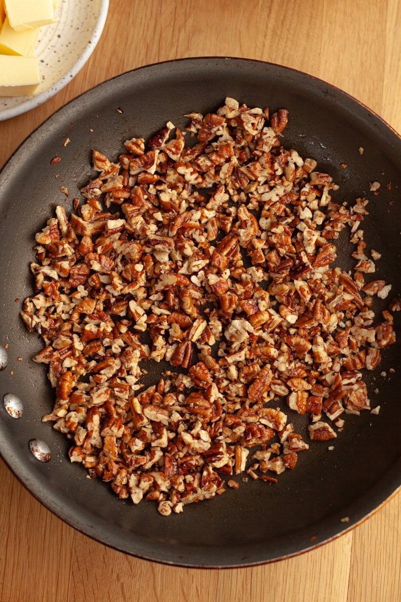 A frying pan with chopped pecans in it.