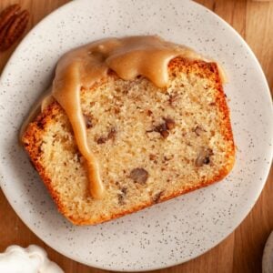 Slice of butter pecan pound cake with a cinnamon brown sugar glaze on a white plate.