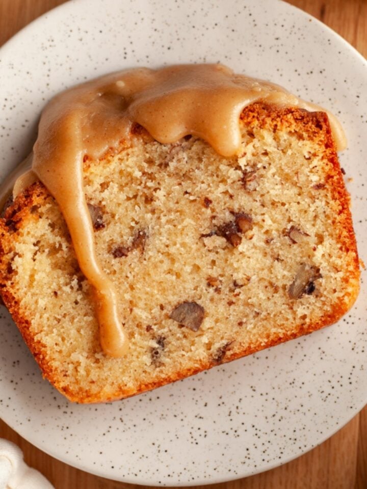 Slice of butter pecan pound cake with a cinnamon brown sugar glaze on a white plate.