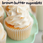 A yellow cupcake with white frosting on a teal cake stand.