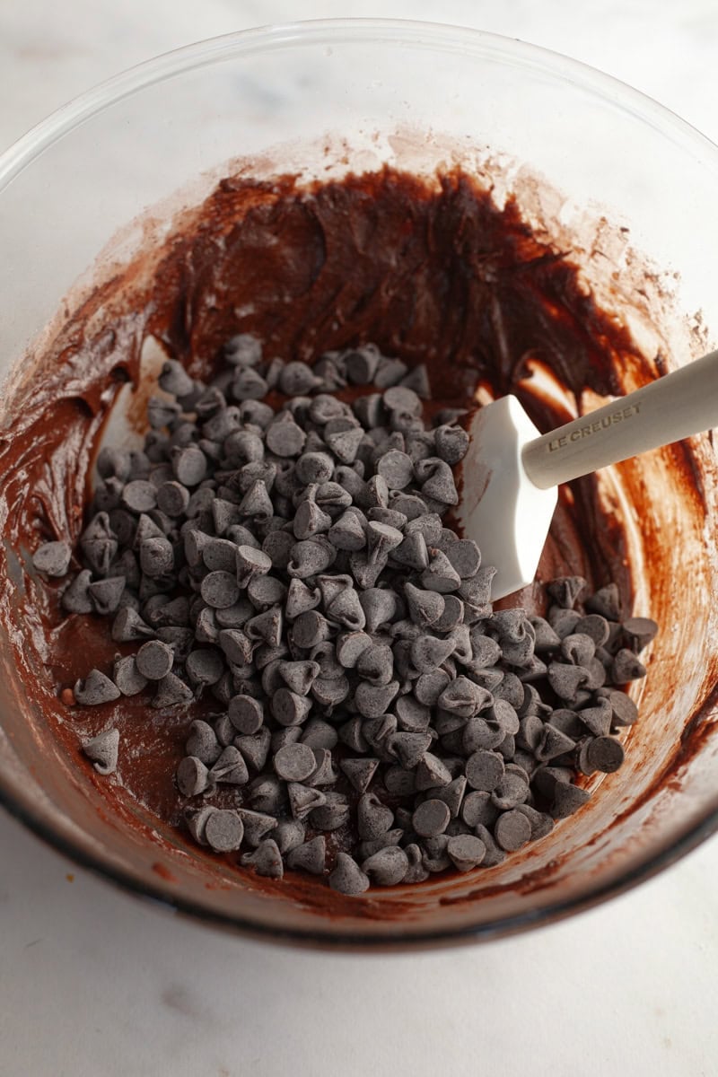 Chocolate cookie dough with chocolate chips in a glass bowl.