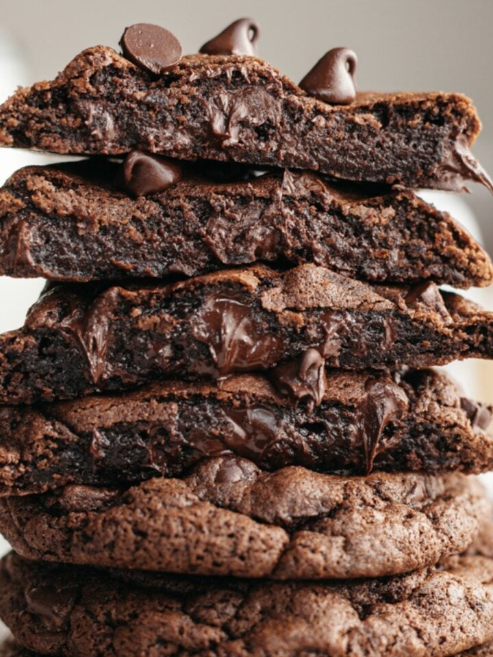 A stack of double chocolate cookies, cut in half so you see melting chocolate chips inside.