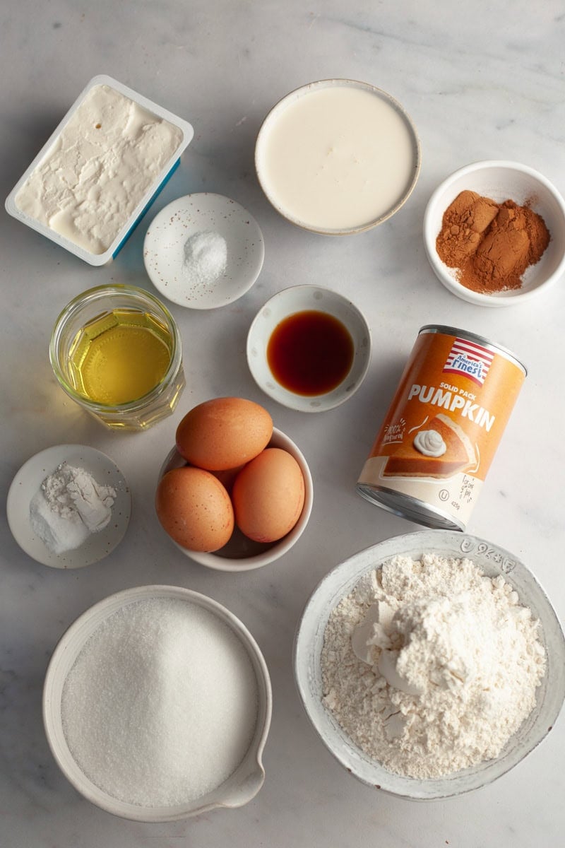 All the ingredients needed to make a pumpkin cake with cream cheese frosting, weighed out into small bowls.