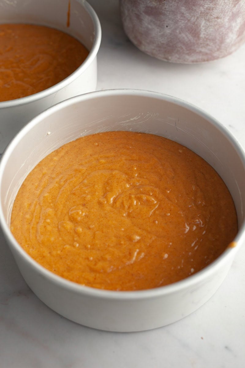 Unbaked pumpkin cake batter in two round cake pans.