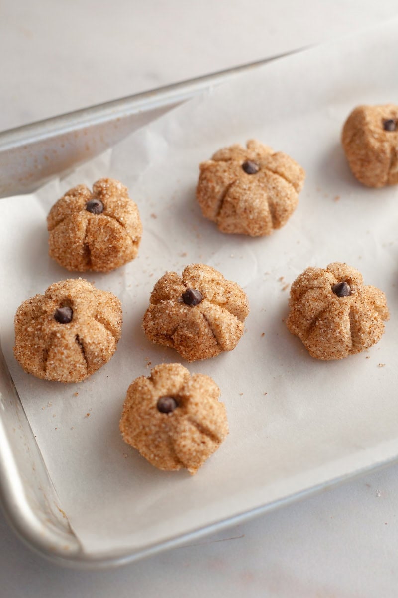 Mini edible sugar cookie pumpkins on parchment paper.