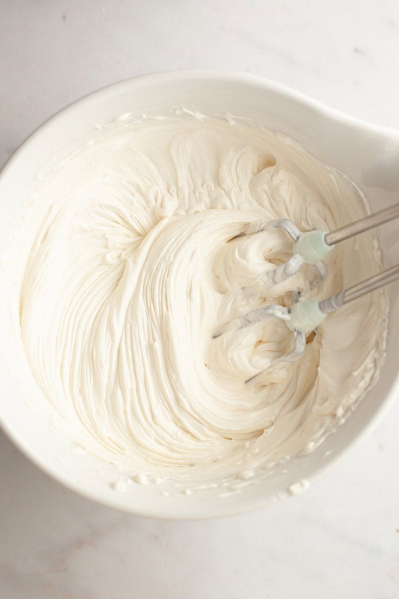 A white bowl with cream cheese frosting.